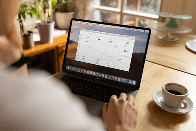 person sat in front of laptop with cup of coffee on the desk