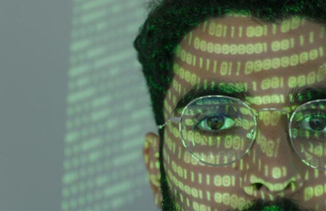 person with binary data reflected in their face and glasses