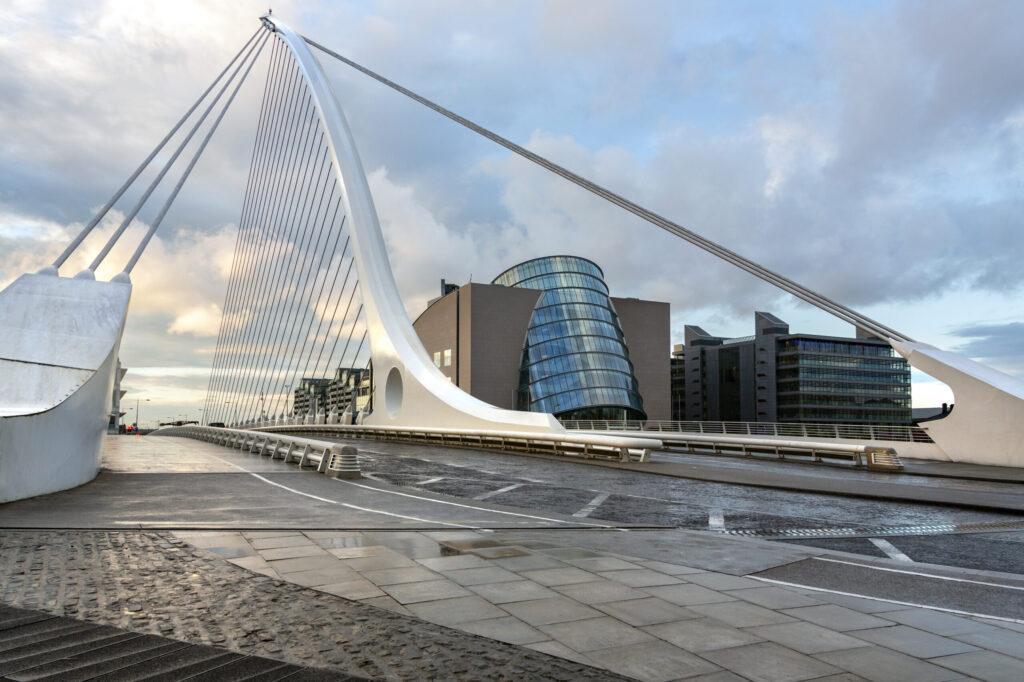 The Samuel Beckett Bridge and the building on the waterfront near the Convention Center - Dublin city center in the Republic of Ireland. This is a cable-stayed bridge that joins Sir John Rogerson's Quay on the south side of the River Liffey to Guild Street and North Wall Quay in the Docklands area. The innovative architect Santiago Calatrava designed this and a number of other bridges and buildings in Ireland.