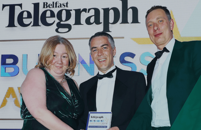 Three people stood holding an award