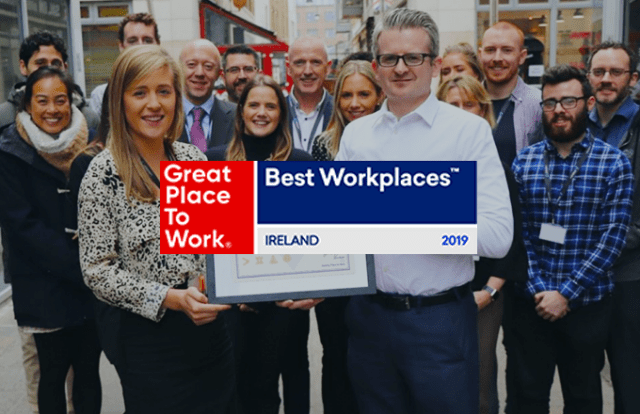 Great Place to Work logo laid over a group of people holding an award