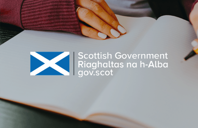 Scottish Government graphic laid over a close up of someone using a notebook