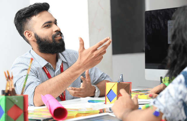 man talking at a table with creative gubbins on it