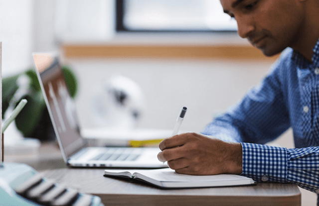 Man at laptop with notebook and pen