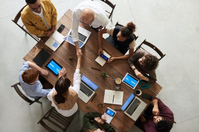 overhead view of a group of people in a meeting. 2 are shaking hands