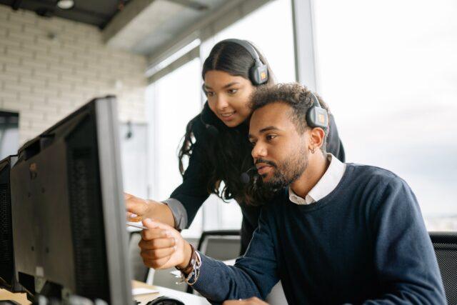 Two people at a laptop in headsets